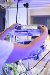 Rückenansicht von Ernte unerkennbar Frau in weißen medizinischen Kittel konzentriert sich auf den Bildschirm und die Anpassung der Einstellungen der modernen digitalen medizinischen Geräten im Krankenhaus - ADSF40444