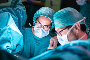 Männlicher Arzt und weibliche Assistentin bereiten saubere Instrumente vor der Operation in einem hell beleuchteten Operationssaal vor - ADSF40515