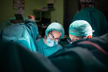 Male doctor and female assistant preparing clean tools before surgery in brightly illuminated operating theater - ADSF40516