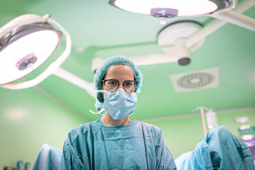 Ärztin in medizinischer Uniform, die eine Operation durch einen Schnitt am Patienten in einem modernen Krankenhaus durchführt - ADSF40523