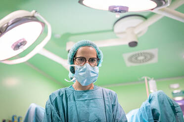 Female doctor in medical uniform performing surgery through cut on patient in modern hospital - ADSF40523