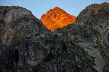 Schneebedeckte Felsen in den Pyrenäen, beleuchtet vom orangefarbenen Licht des Sonnenuntergangs - ADSF40560