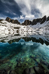 Atemberaubende wilde Naturlandschaft mit rauen schneebedeckten felsigen Gipfeln, die sich in der glatten Wasseroberfläche eines ruhigen klaren Sees in den Pyrenäen spiegeln - ADSF40564