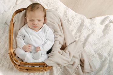 Von oben liegendes und schlafendes Kleinkind im Korb mit warmer Decke zu Hause - ADSF40596