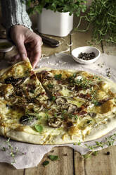 Anonymous person grabbing a delicious mushrooms rustic pizza - ADSF40599