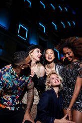 Group of stylish multiracial friends walking together on city street for party at night - ADSF40736