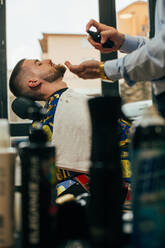 Ein Barbier schneidet den Bart eines Mannes mit einem Rasiermesser in einem Barbershop - ADSF40878