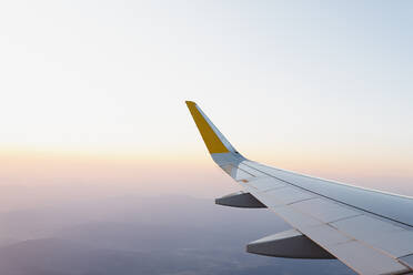 Wing of modern aircraft flying in cloudy blue sky during trip - ADSF40990