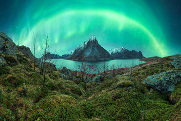 Herrlicher Blick auf die bunten Nordlichter, die den Nachthimmel über den felsigen Bergen in der Nähe des Sees im Winter auf den Lofoten erleuchten - ADSF41008