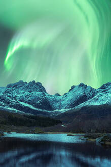 Herrlicher Blick auf die bunten Nordlichter, die den Nachthimmel über den felsigen Bergen in der Nähe des Sees im Winter auf den Lofoten erleuchten - ADSF41011