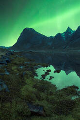 Herrlicher Blick auf die bunten Nordlichter, die den Nachthimmel über den felsigen Bergen in der Nähe des Sees im Winter auf den Lofoten erleuchten - ADSF41012