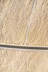 Luftaufnahme eines langen Highways, der durch das unwegsame Gelände des Death Valley National Park, Kalifornien, führt, an einem sonnigen Tag in den Vereinigten Staaten - ADSF41019