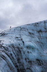 Abgeschnittene unerkennbare himmlische Eisformation des Vatnajokull-Gletschers mit Touristen vor einem wolkenverhangenen grauen Himmel an einem Wintertag in Island - ADSF41040