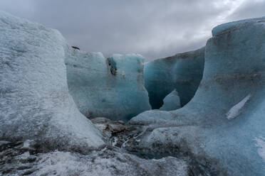Unebene Eisformationen des Vatnajokull-Gletschers vor einem wolkenverhangenen grauen Himmel an einem Wintertag in Island - ADSF41044