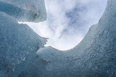 Von unten raue Eisformationen des Vatnajokull-Gletschers vor blauem Himmel mit weißen Wolken an einem Wintertag in Island - ADSF41045