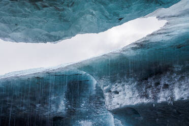 Sauberes Wasser, das von zerbrechlichen, transparenten Eiszapfen in der Eishöhle des Vatnajokull-Gletschers in Island fällt - ADSF41064