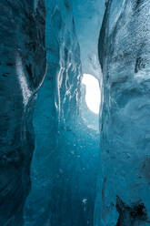 Von unten Eisspitzen, die das Loch in der Höhlendecke umgeben, gegen einen bedeckten grauen Himmel an einem Wintertag im Vatnajokull-Nationalpark in Island - ADSF41070