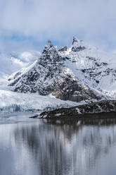 Breathtaking scenery of rocky mountains covered with snow near frozen lake against cloudy blue sky in Vatnajokull National park - ADSF41079