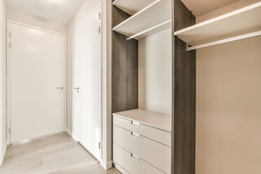 Stilvoller großer weißer Kleiderschrank in Wandnähe und Regale in einem hellen geräumigen Zimmer - ADSF41094
