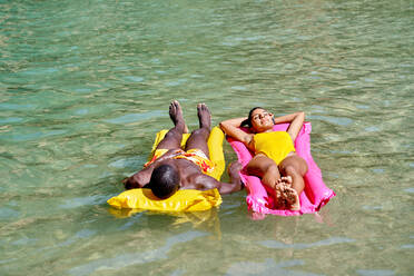 Von oben Drohne Blick auf multirassischen Mann und Frau faulenzen auf aufblasbaren Schwimmern in sauberen See Wasser während des Sommerurlaubs - ADSF41105