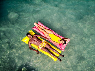 Von oben Drohne Blick auf multirassischen Mann und Frau faulenzen auf aufblasbaren Schwimmern in sauberen See Wasser während des Sommerurlaubs - ADSF41113