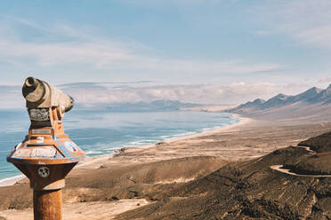 Aged rostigen Turm Betrachter Teleskop auf felsigen Berg über schäumenden Ozean gegen bewölkten blauen Himmel in Fuerteventura - ADSF41275