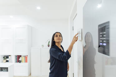 Woman using smart home device on wall - MEUF08640