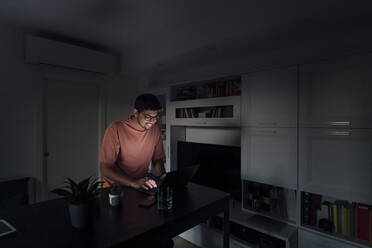 Lächelnder Mann mit Laptop im Wohnzimmer zu Hause - MEUF08666