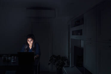 Junge Frau benutzt Laptop im Wohnzimmer zu Hause - MEUF08679