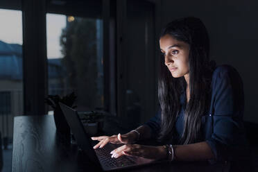 Frau benutzt Laptop auf Tisch zu Hause - MEUF08681