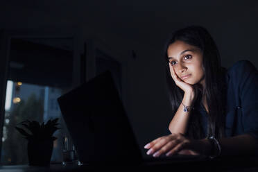 Frau mit Kopf in der Hand schaut auf Laptop - MEUF08686