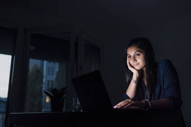 Lächelnde junge Frau, die zu Hause einen Laptop benutzt - MEUF08687