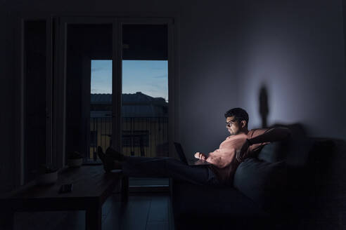 Junger Mann benutzt Laptop in einem Zimmer zu Hause - MEUF08694