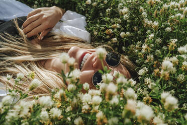 Happy woman lying on uncultivated meadow of wildflowers - MDOF00297