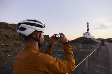 Radfahrer fotografiert bei Sonnenaufgang mit seinem Smartphone - JPTF01104
