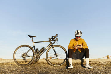Junger Radfahrer mit Smartphone unter freiem Himmel - JPTF01114