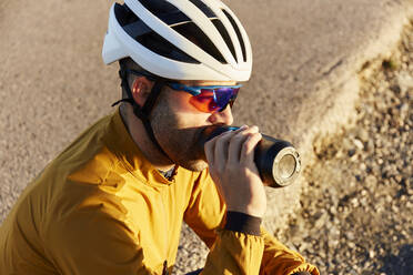 Thirsty cyclist drinking water on sunny day - JPTF01115