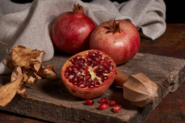 From above fresh whole pomegranate and seeds arranged on wooden board near squeezer - ADSF41440