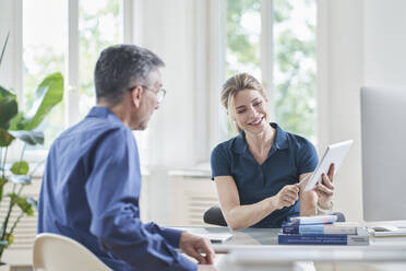 Smiling female doctor discussing over tablet PC with patient in medical practice - RORF03091