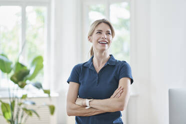 Cheerful physical therapist standing with arms crossed in medical practice - RORF03102