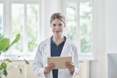 Smiling female doctor standing with tablet PC at medical practice - RORF03115