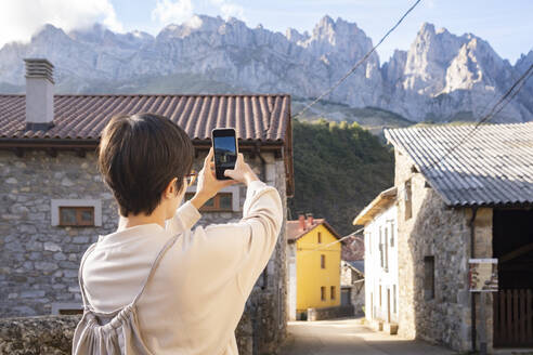 Spanien, Kastilien und Leon, Posada de Valdeon, Touristin fotografiert Steinhäuser in den Picos de Europa - MMPF00525