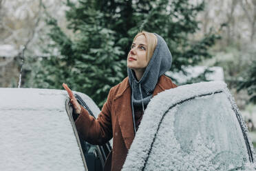 Thoughtful woman at car covered with snow in winter - VSNF00143