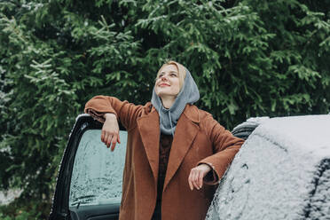 Smiling woman at car covered with snow in winter - VSNF00144