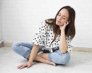 Smiling woman with eyes closed sitting on floor at home - JBYF00169