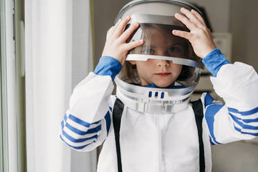 Girl wearing space helmet at home - EBBF07282