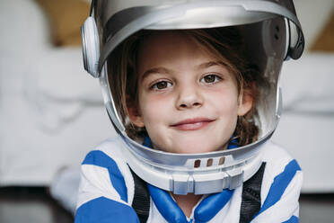 Smiling girl wearing space costume and helmet at home - EBBF07293