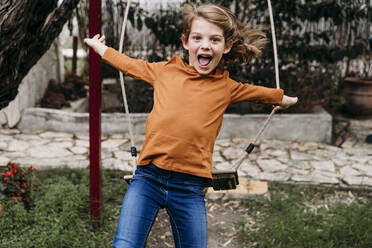 Playful girl jumping from swing in garden - EBBF07306