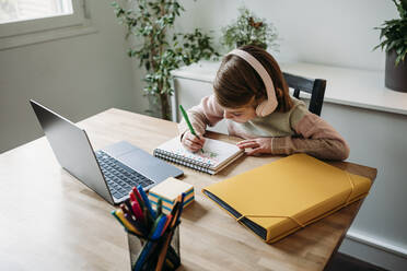 Girl doing homework sitting with laptop at table - EBBF07311