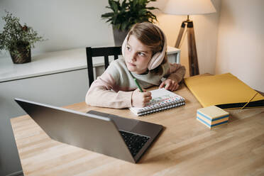 Girl sitting with laptop studying at table at home - EBBF07314